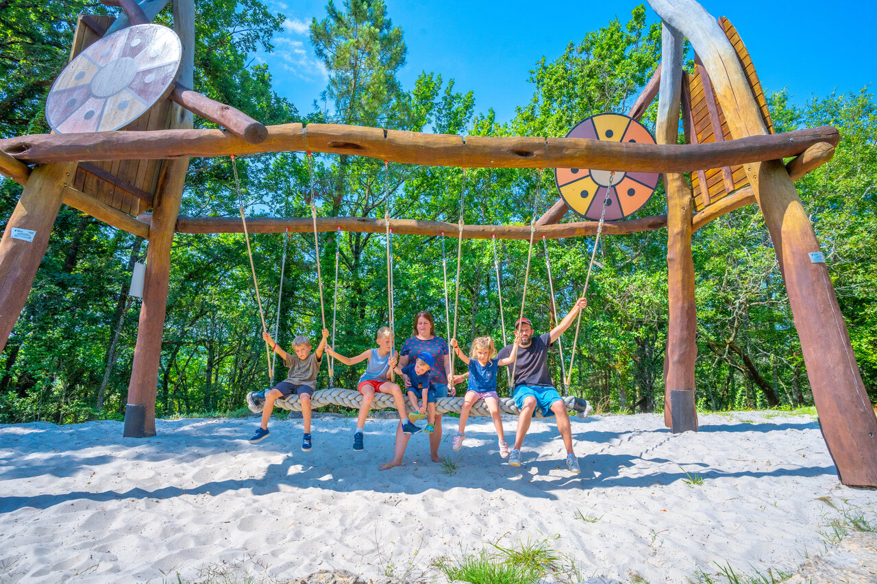 Familia disfrutando de un columpio gigante en arena en el camping CAPFUN Hauts de Ratebout en STE FOY DE BELVES (24).