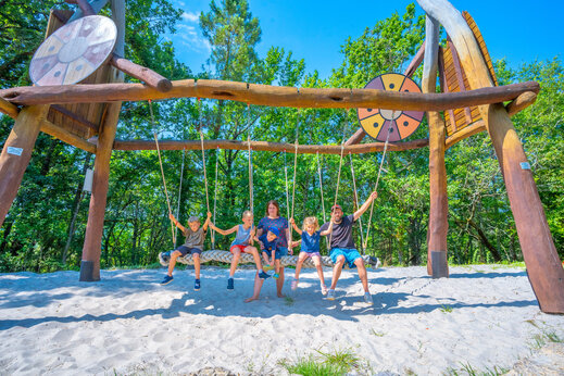 Columpio gigante de madera con familia sonriente en el camping CAPFUN Hauts de Ratebout en STE FOY DE BELVES (24)