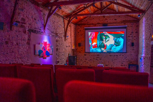 Sala de cine interior con pantalla de proyecci�n y asientos rojos en el camping CAPFUN Hauts de Ratebout en STE FOY DE BELVES (24).