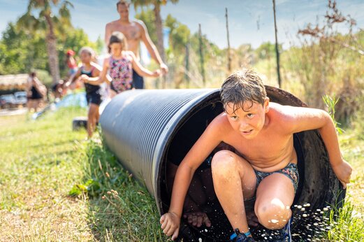 Ni�o saliendo de un t�nel acu�tico, juego en el camping CAPFUN Hauts de Ratebout en STE FOY DE BELVES (24).