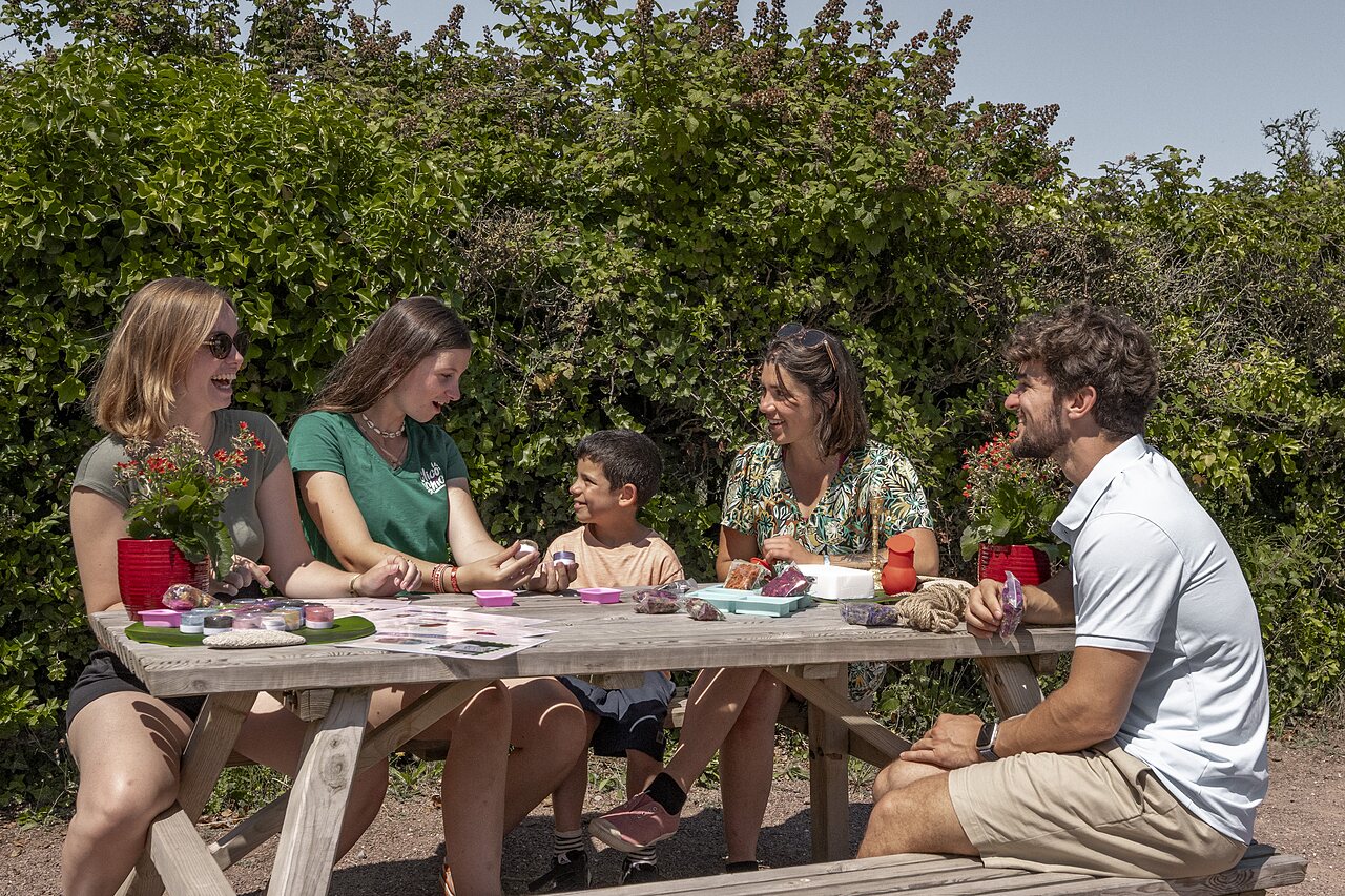 Familia participando en taller creativo al aire libre en camping CLICOCHIC Havre de Berni�res.