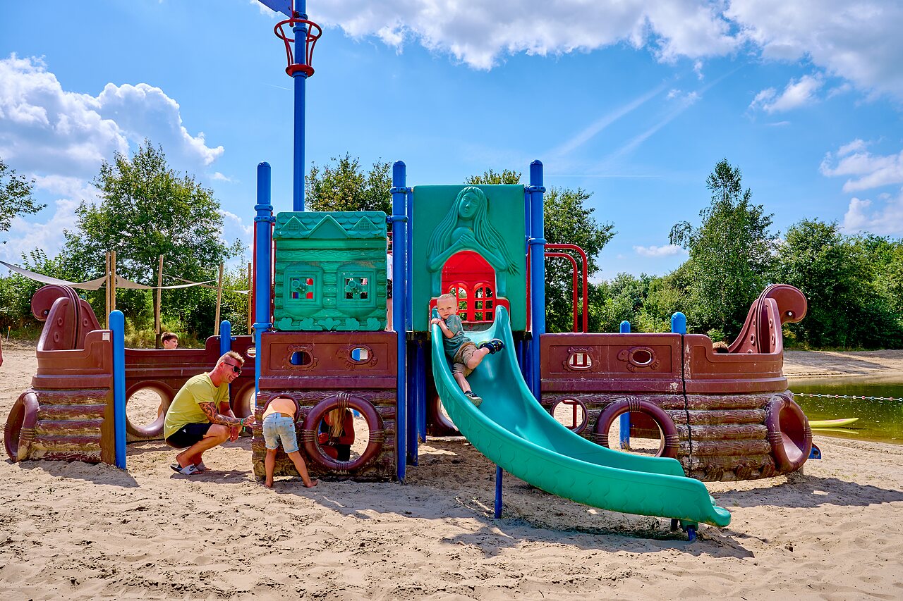 Ni�os jugando en parque infantil pirata con tobog�n en camping CAPFUN Heino.