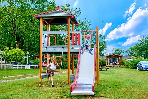 Zona de juegos con tobogán y niños divirtiéndose en el camping CAPFUN Heino en Heino.