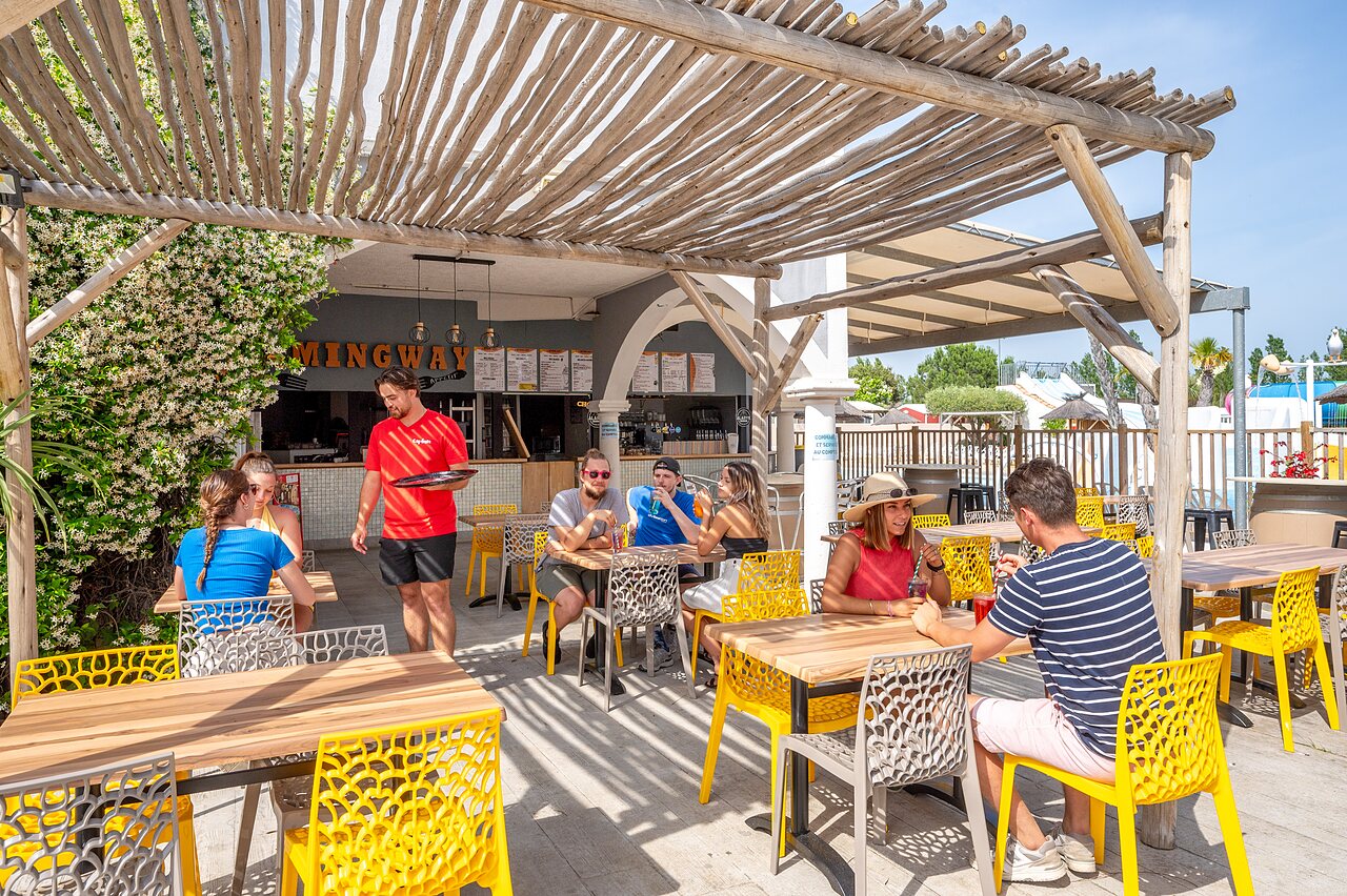 Terraza de restaurante exterior con clientes y camarero en CAPFUN Hermitage, SERIGNAN (34).