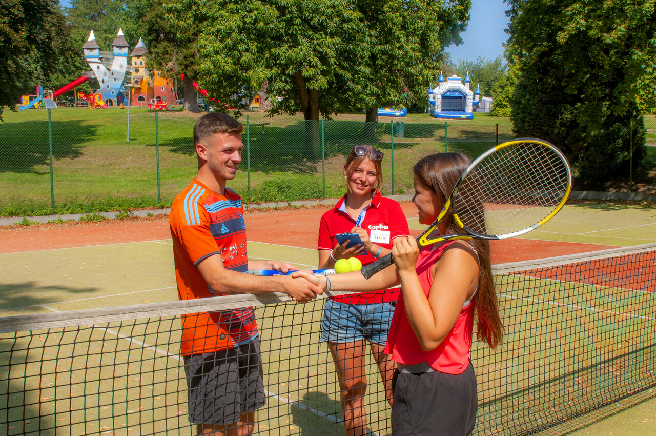 Jugadores de tenis y animador en la cancha al camping CAPFUN Hirondelle en Oteppe.