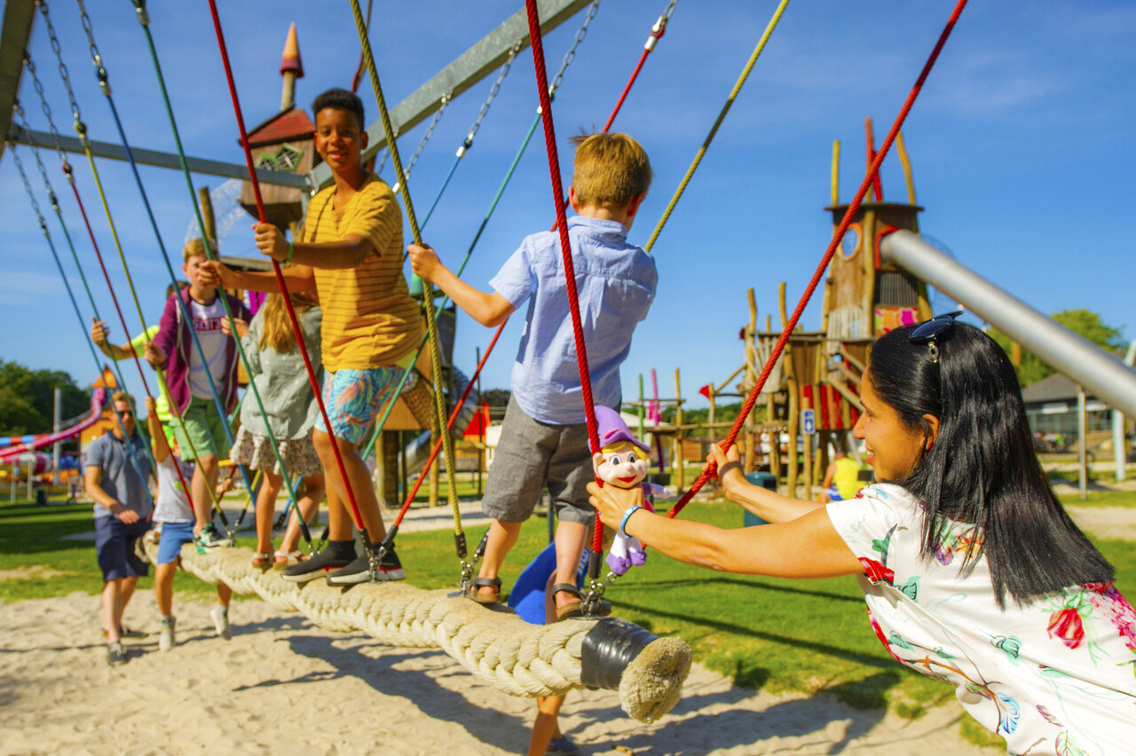Zona de juegos con puente de cuerda y ni�os en el camping CAPFUN Hirondelle en Oteppe.