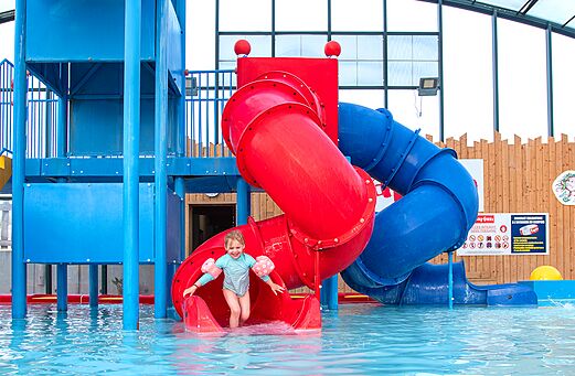 Tobog�n acu�tico y piscina con ni�o sonriente en el camping CAPFUN Hirondelle en Oteppe.