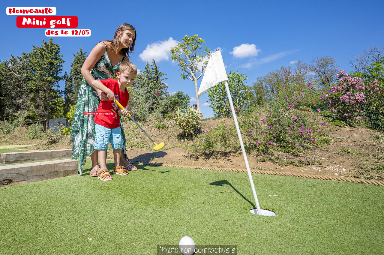 Ni�o y mujer jugando al minigolf en el camping CAPFUN Huttes en Saint-Denis d'Ol�ron.