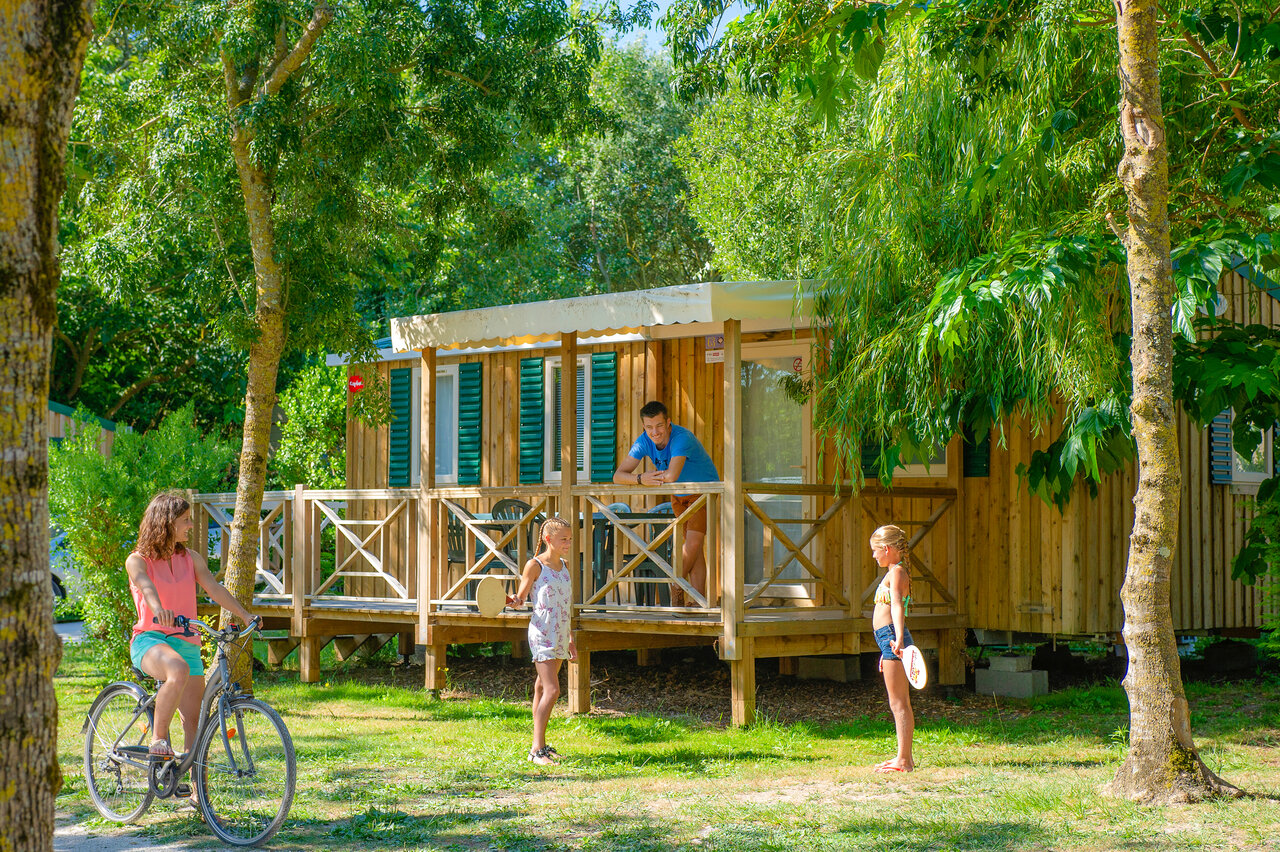 Mobil home de madera con terraza, familia y bicicleta en el camping CAPFUN Huttes en Saint-Denis d'Ol�ron (17).