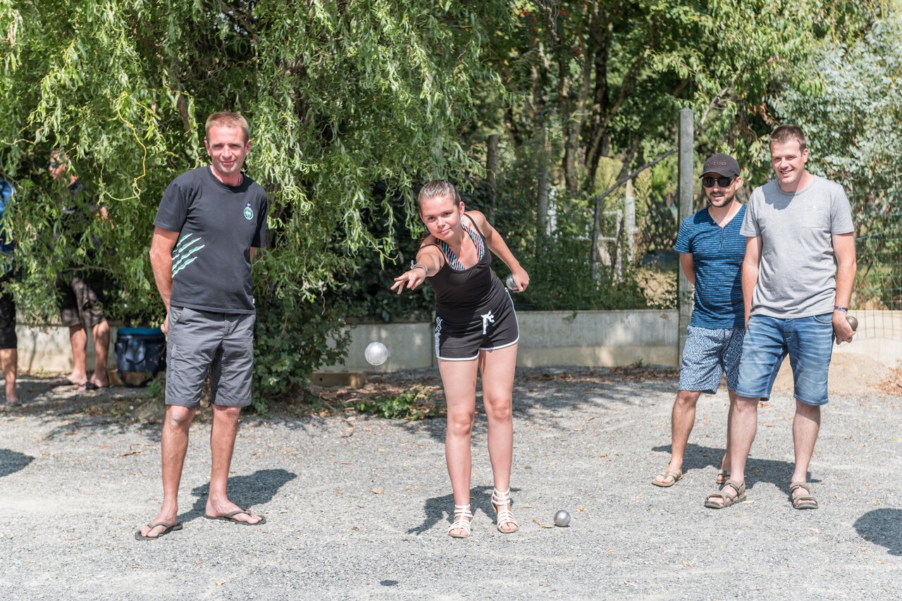 J�venes y adultos jugando a la petanca en una pista, en el camping CAPFUN Huttes en Saint-Denis d'Ol�ron (17).