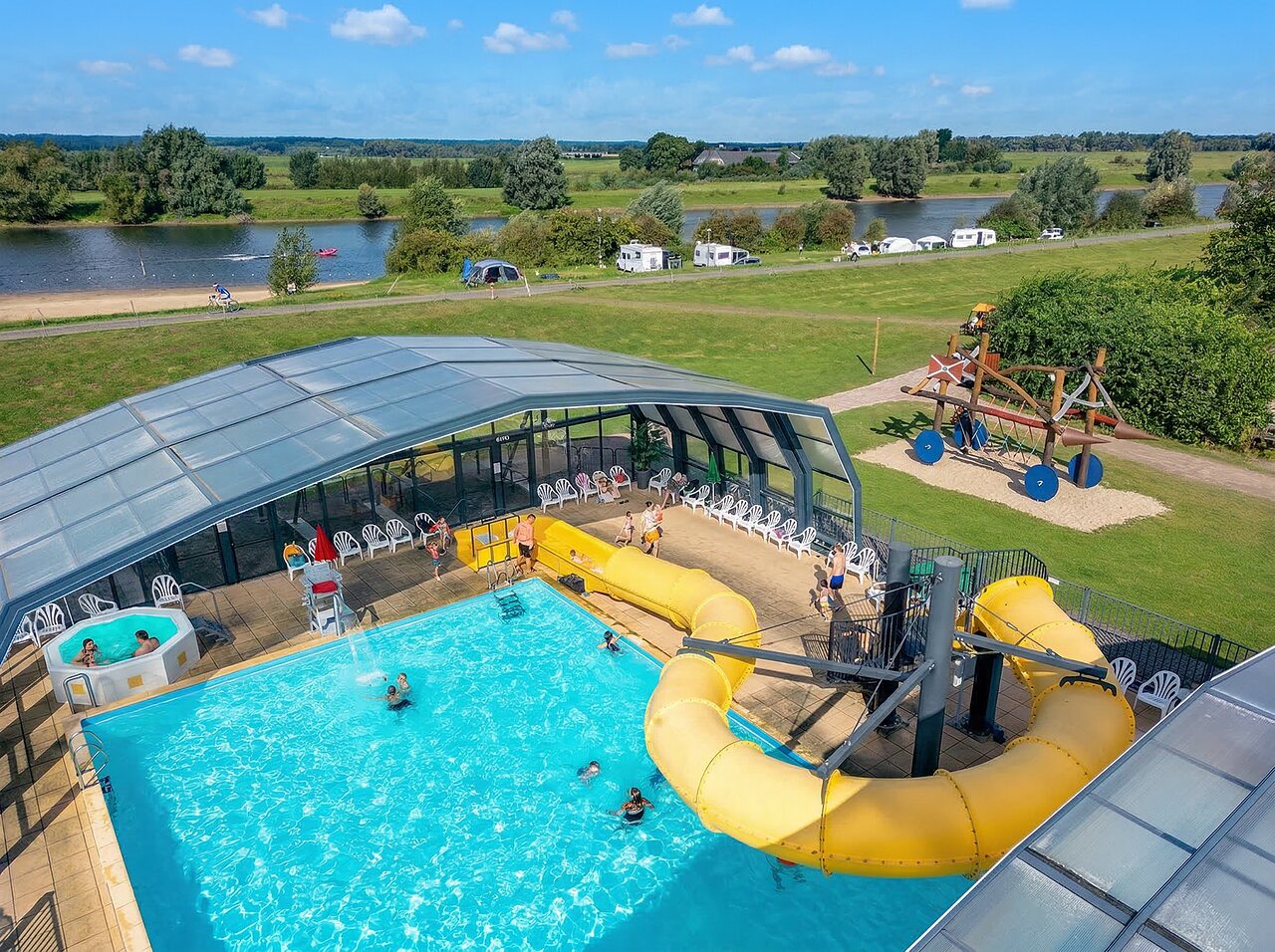 Piscina exterior con tobog�n gigante, jacuzzi y zona de juegos en el camping CAPFUN IJsselstrand en Doesburg.