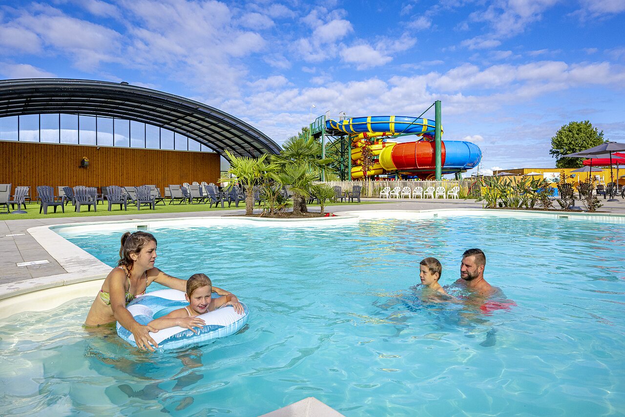 Familia disfrutando piscina exterior y toboganes gigantes en camping CAPFUN IJsselstrand, Doesburg.