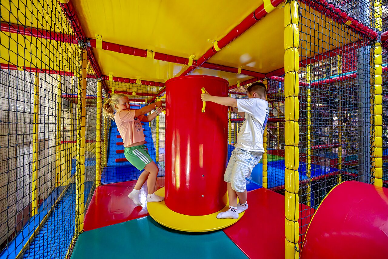 Ni�os jugando en una colorida estructura de juegos interior en el camping CAPFUN IJsselstrand en Doesburg.