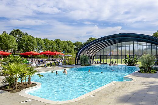 Piscina exterior y cubierta con bañistas en el camping CAPFUN IJsselstrand en Doesburg.