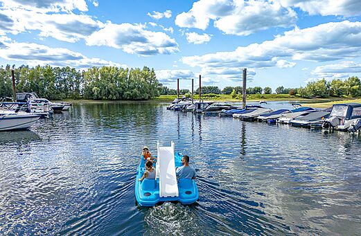 Bote a pedales con tobogán y familia en el agua en el camping CAPFUN IJsselstrand en Doesburg.