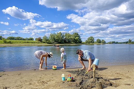 Familia construyendo castillos de arena en playa, camping CAPFUN IJsselstrand Doesburg.