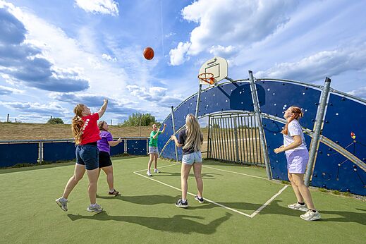 Cancha multideportiva y jóvenes jugando baloncesto en camping CAPFUN IJsselstrand en Doesburg.