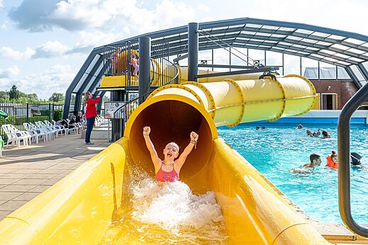 Tobogán acuático amarillo y piscina exterior en el camping CAPFUN IJsselstrand en Doesburg.