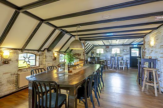 Restaurante y bar con mesa de madera larga y paredes de ladrillo en el camping CAPFUN IJsselstrand en Doesburg.