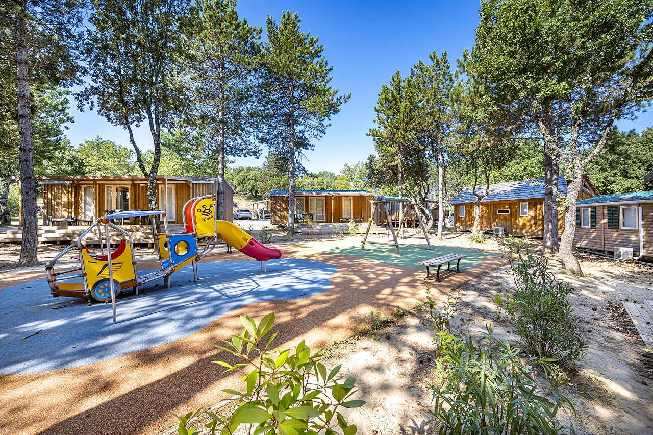 Zona de juegos colorida con tobog�n y columpios, casas m�viles en camping CAPFUN Imbours en LARNAS (07).