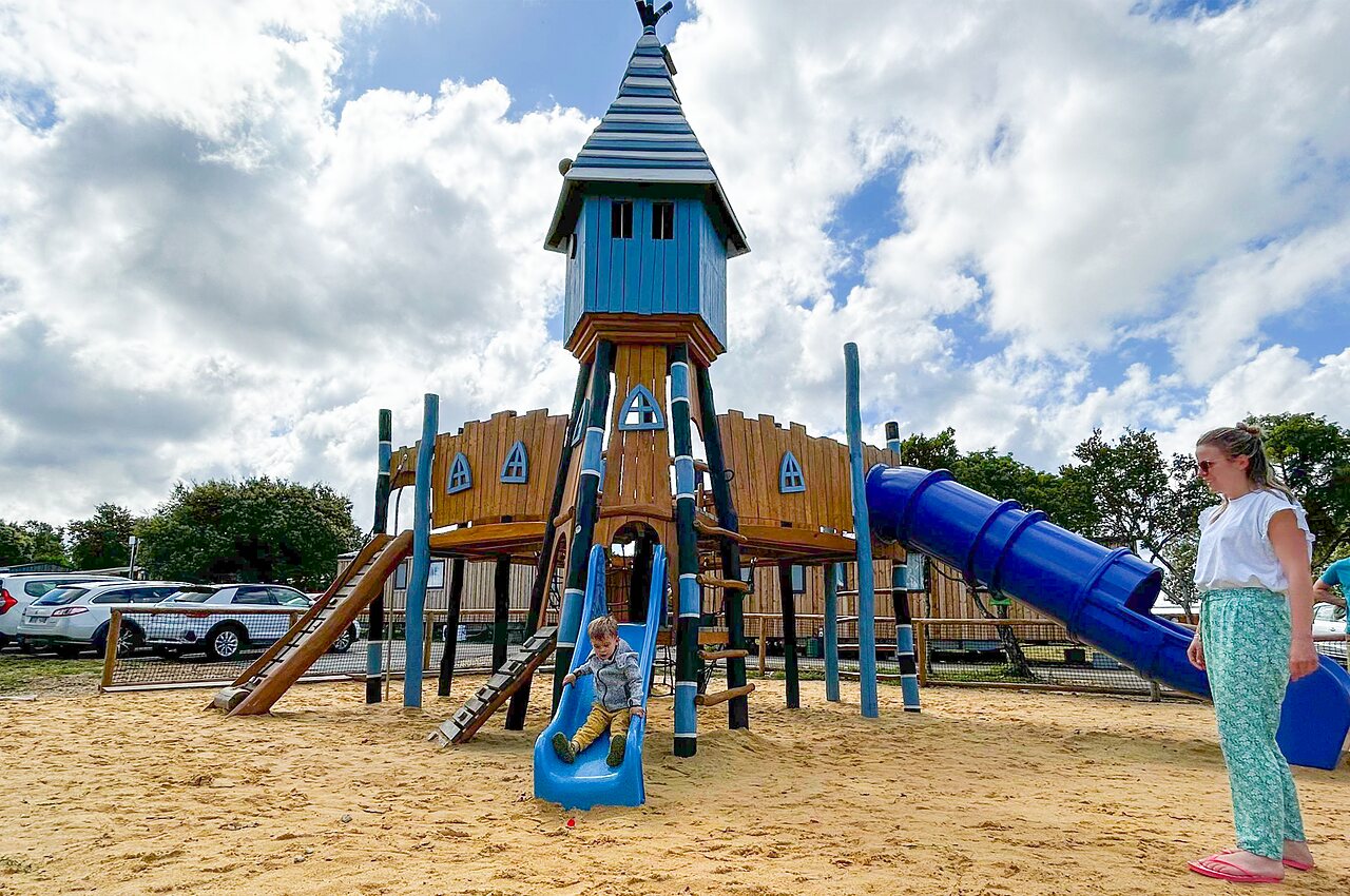 Gran parque infantil de madera, tobog�n azul, ni�o en el camping CAPFUN Imbours en LARNAS (07).
