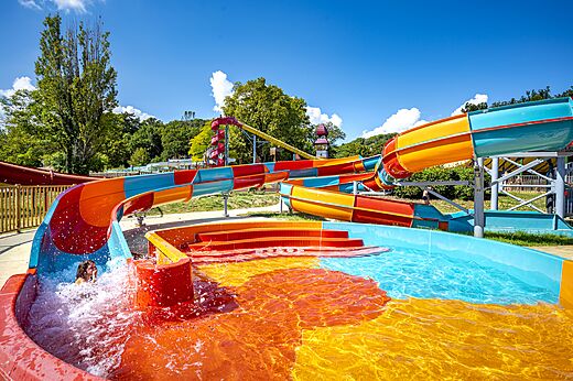 Toboganes acuáticos coloridos y piscina en el camping CAPFUN Imbours en LARNAS (07).
