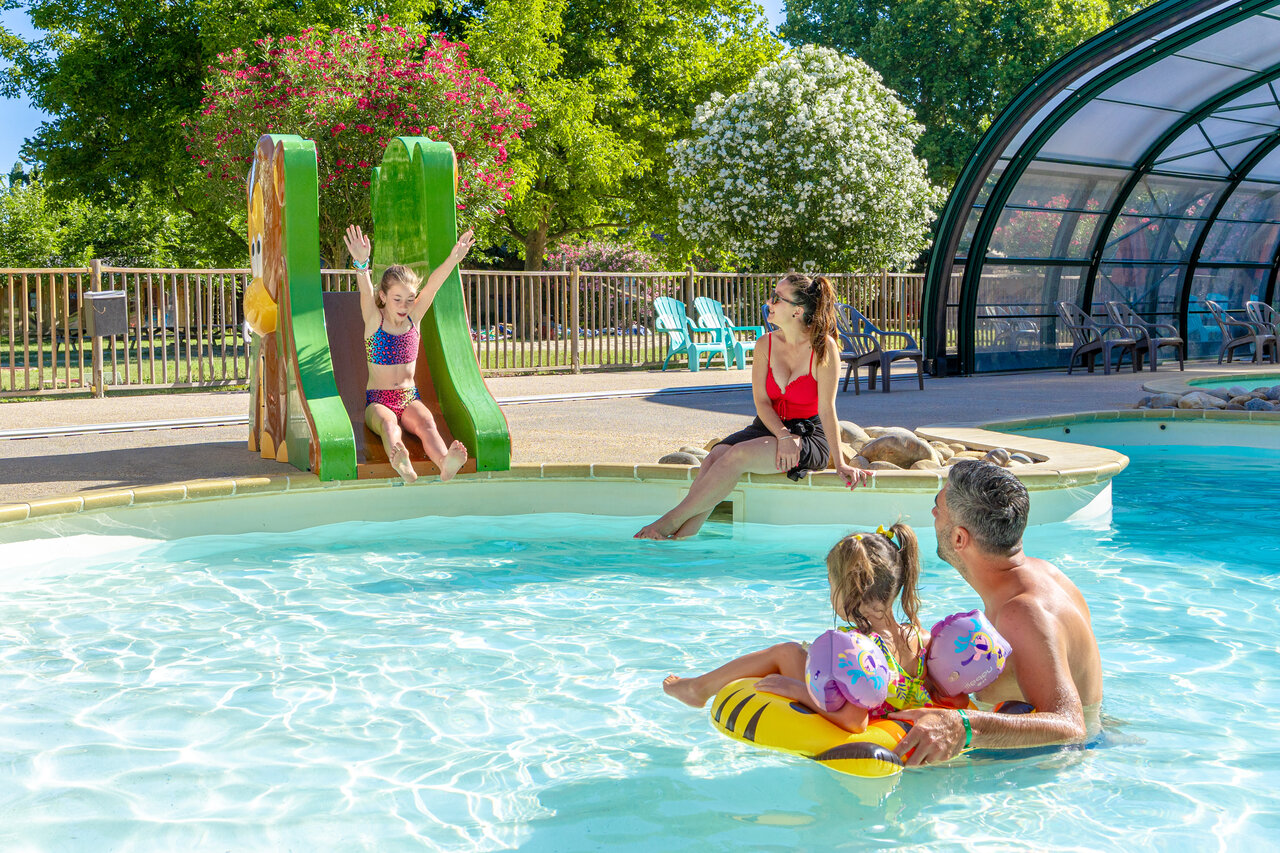 Ni�a en tobog�n y familia disfrutando de la piscina en el camping CAPFUN Jantou en LE THOR (84).
