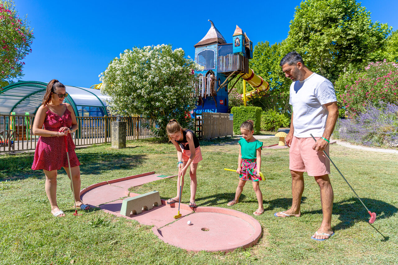 Familia jugando minigolf con zona de juegos y piscina en el camping CAPFUN Jantou en LE THOR (84).