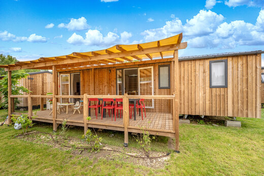 Mobil-home de madera, terraza cubierta, sillas rojas, camping CAPFUN Jantou (84).