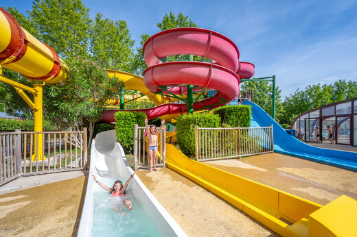 Niños disfrutando de toboganes acuáticos coloridos en el camping CAPFUN Jantou en LE THOR (84).