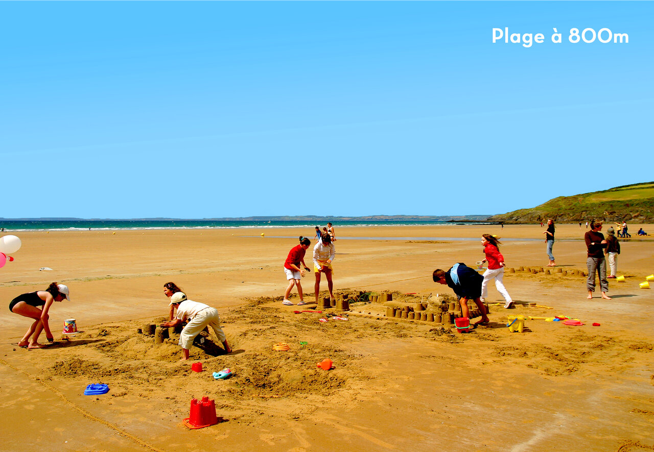 Playa de arena, familias construyendo castillos. Camping CAPFUN Kervel en PLONEVEZ PORZAY.