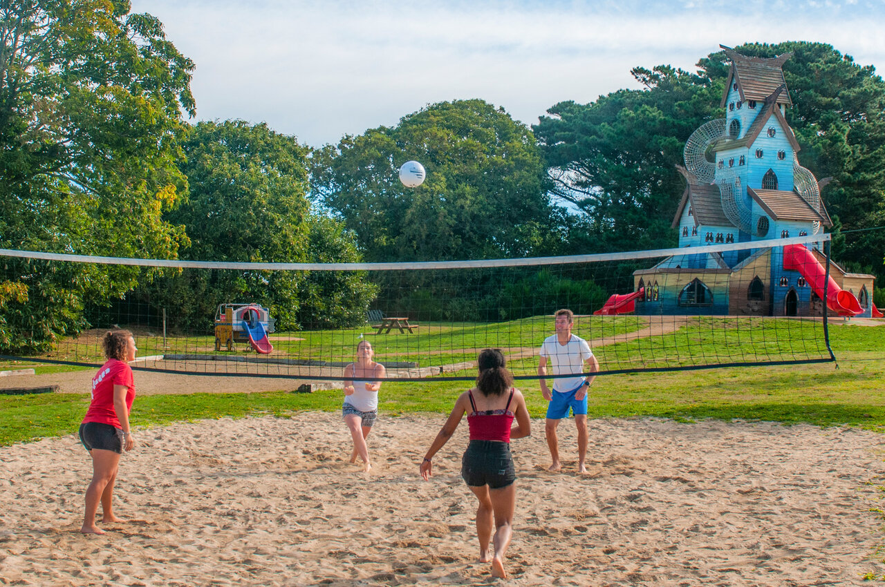 Cancha de voleibol de playa con jugadores y estructura de juegos en el camping CAPFUN Kervel en PLONEVEZ PORZAY.