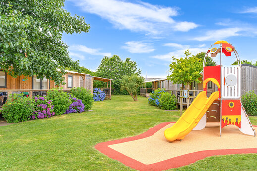 Zona de juegos con tobog�n y Mobil-homes en camping CAPFUN Kervel, PLONEVEZ PORZAY (29).