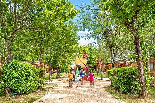 Zona de juegos colorida con tobogán y Mobil-homes sombreados en el camping VAGUES OCEANES Labeiller en Saint Victor de Malcap.