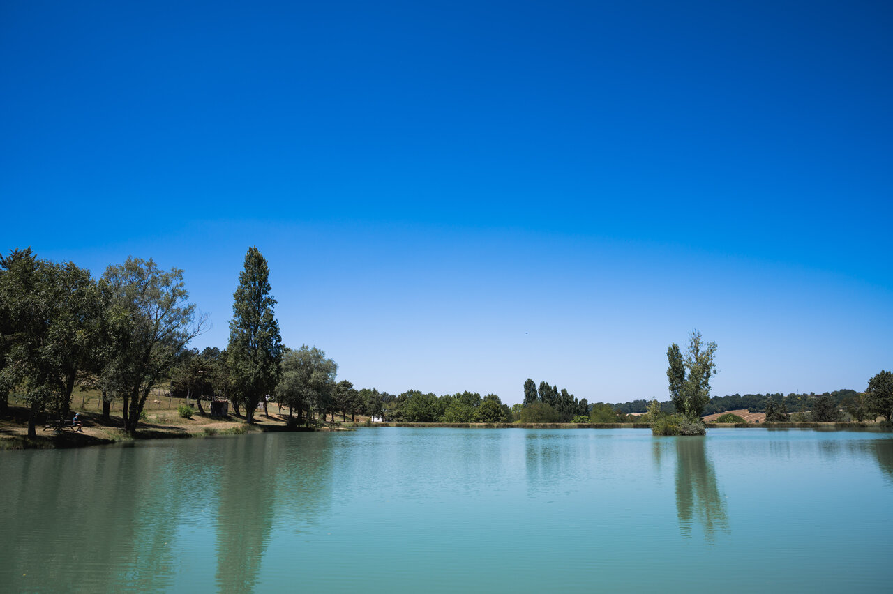 Gran lago tranquilo rodeado de �rboles verdes en el camping CAPFUN Lac des 3 Vall�es en Lectoure (32).