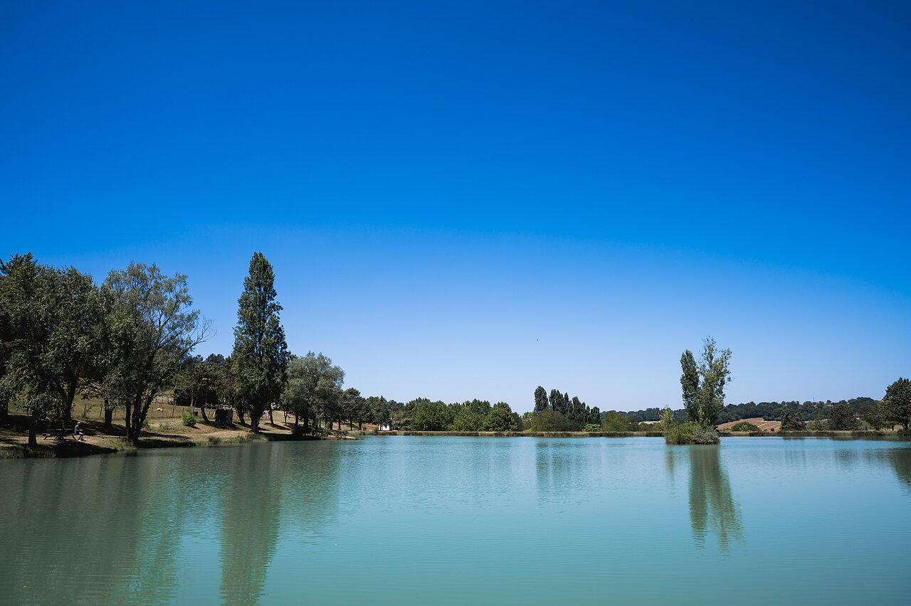 Gran lago natural rodeado de �rboles en el camping CAPFUN Lac des 3 Vall�es en Lectoure.