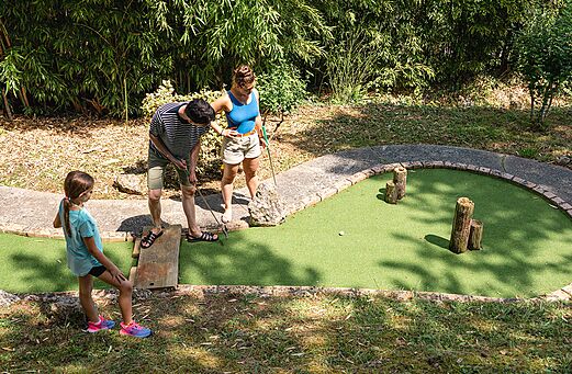 Familia jugando al minigolf en un campo verde en el camping CAPFUN Lac des 3 Vall�es en Lectoure (32).