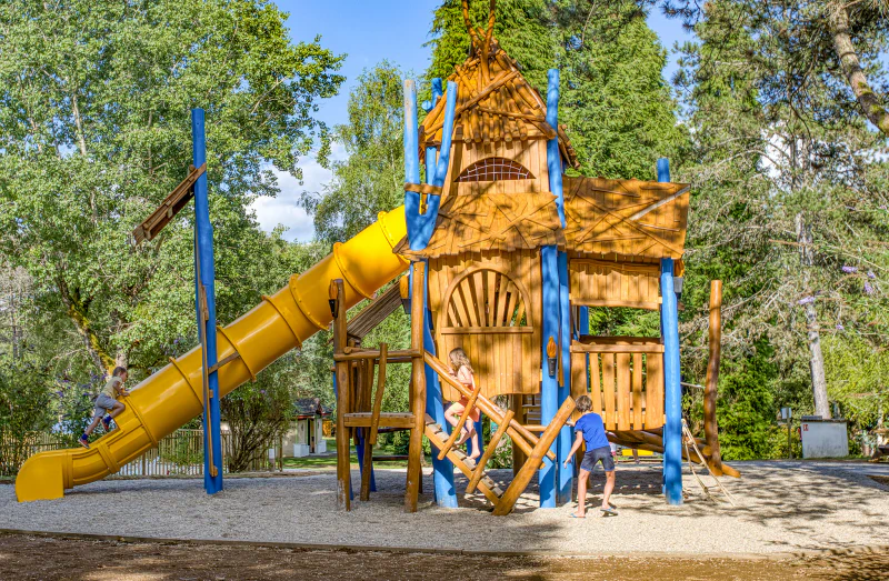Parque infantil de madera con tobog�n amarillo en camping CLICOCHIC Lac de Miel en Beynat (19).