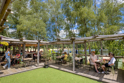 Terraza de restaurante sombreada con comensales, en el camping CLICOCHIC Lac de Miel en Beynat (19).