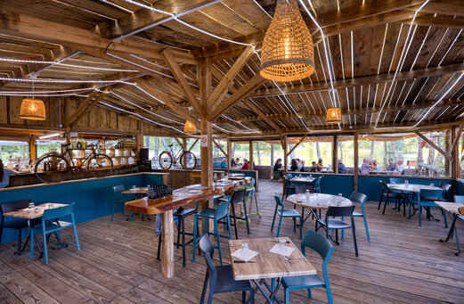 Restaurante y bar de madera con vistas al lago en el camping CLICOCHIC Lac de Miel en Beynat (19).