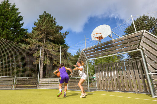 Dos mujeres jugando baloncesto en cancha multideporte en el camping CLICOCHIC Lac de Miel en Beynat (19).