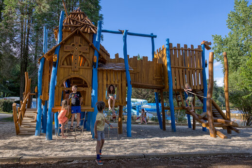 Parque infantil de madera con niños en el camping CLICOCHIC Lac de Miel en Beynat (19).