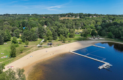 Playa de arena, lago y pontón en el camping CLICOCHIC Lac de Miel en Beynat (19).