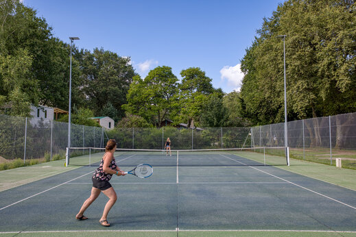 Cancha de tenis exterior con jugadores en camping CLICOCHIC Lac de Miel, Beynat.