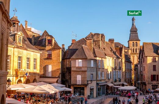 Plaza hist�rica animada con terrazas de restaurantes en Sarlat, Dordo�a.