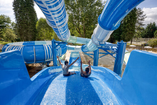 Toboganes acuáticos azules, niños divirtiéndose en camping CLICOCHIC Lac de Miel en Beynat.