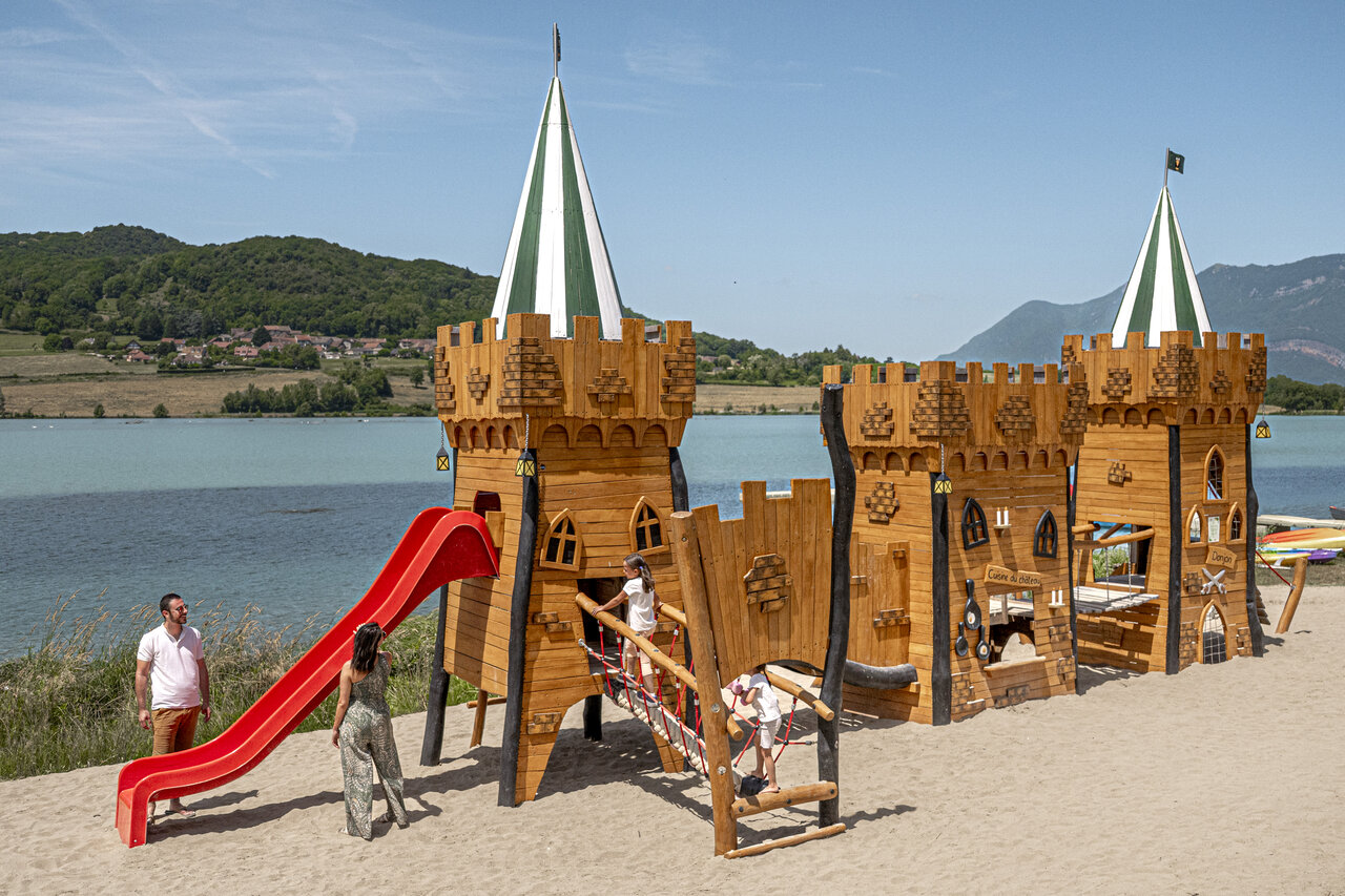 Gran parque infantil castillo de madera con tobog�n junto al lago en el camping CLICOCHIC Lac du Lit du Roi en Massignieu-de-Rives (01).