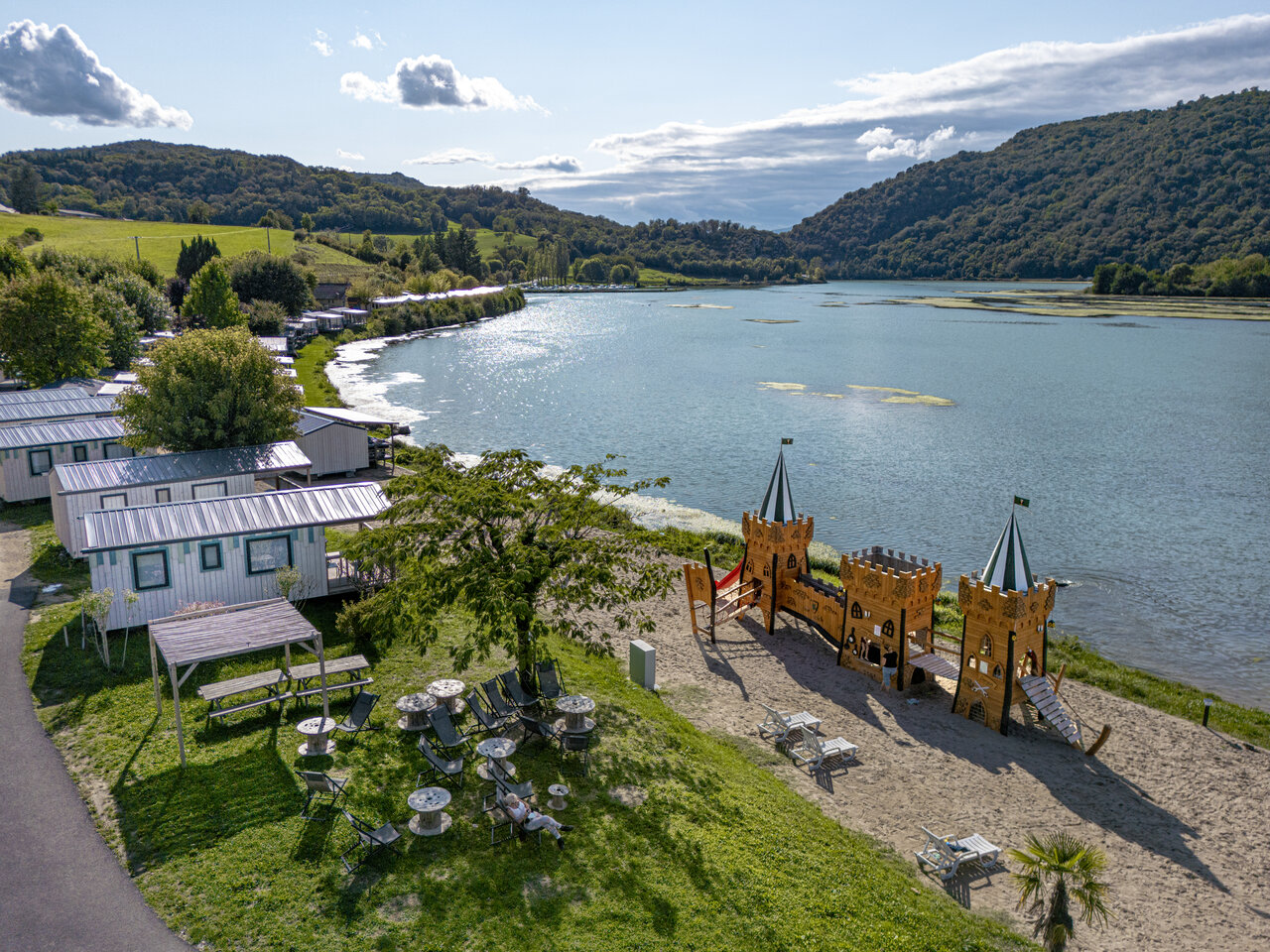Vista a�rea del lago, casas m�viles y parque infantil en el camping CLICOCHIC Lac du Lit du Roi en Massignieu-de-Rives (01).