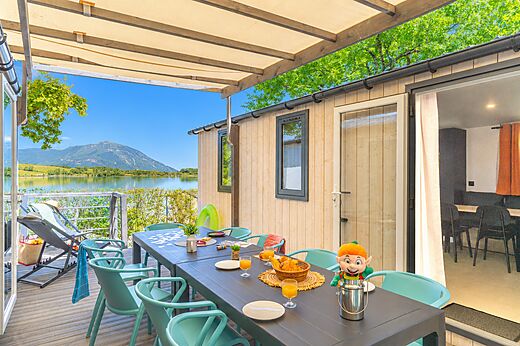 Mobil-home con terraza, mesa, sillas, vista al lago en el camping CLICOCHIC Lac du Lit du Roi en Massignieu-de-Rives (01).