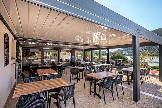 Terraza de restaurante exterior con mesas y sillas en el camping CLICOCHIC Lac du Lit du Roi.